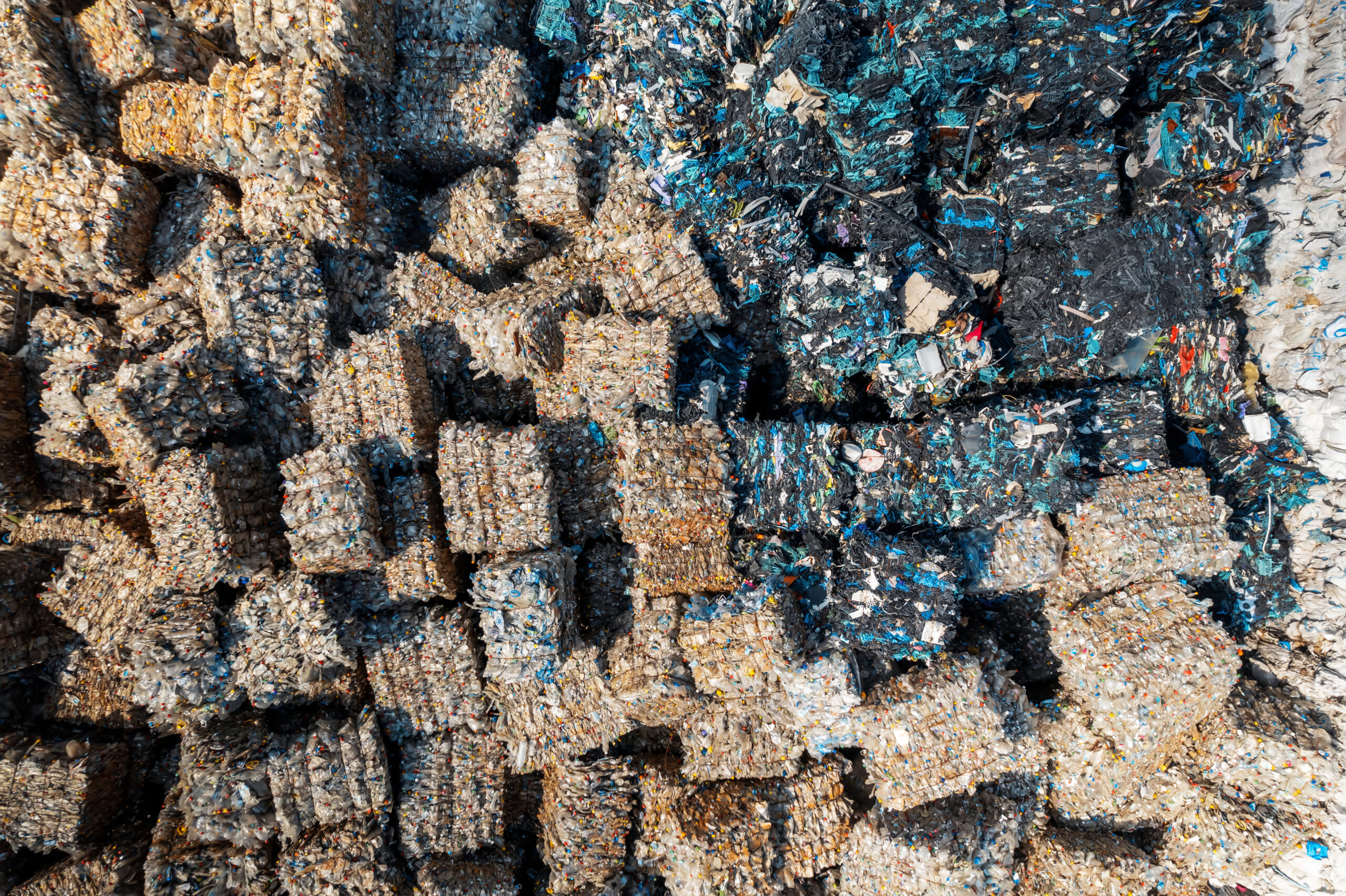 Multiple cubes of compressed plastic garbage near the waste recycling factory in open air. Vertical view